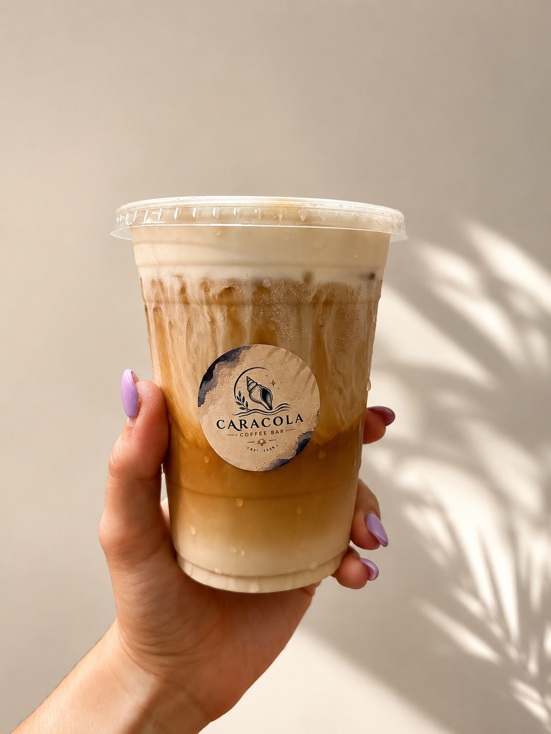 Café frío de Caracola Coffee Bar sostenido a la luz del sol